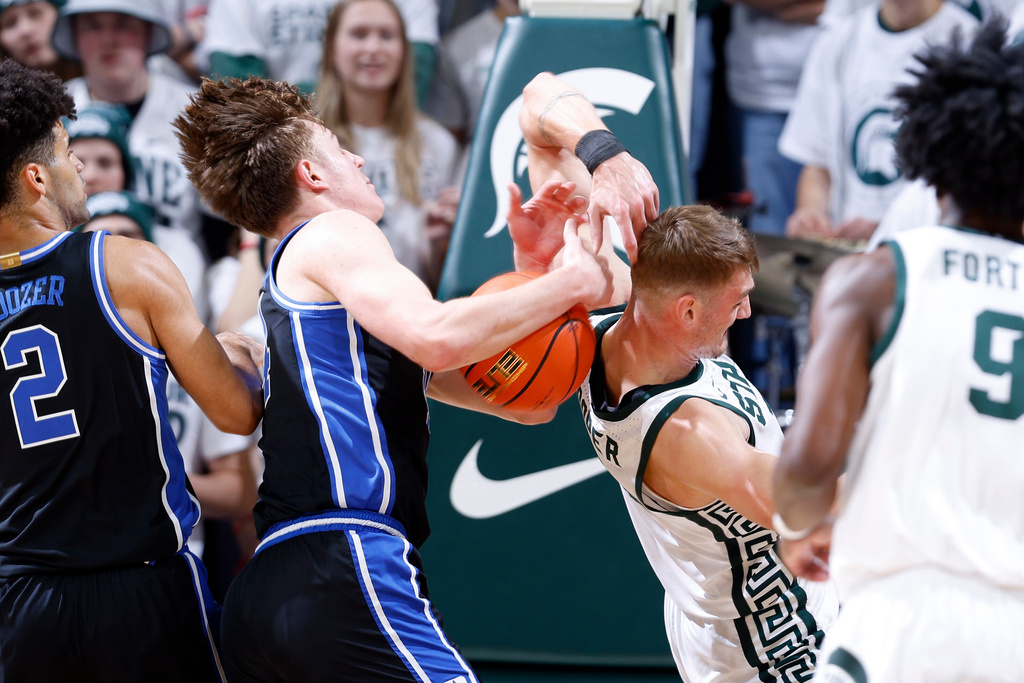 Michigan State center Carson Cooper, right, and Duke guard Nikolas Khamenia (14) battle for a rebound during the first half of an NCAA college basketball game, Saturday, Dec. 6, 2025, in East Lansing, Mich. (AP Photo/Al Goldis)