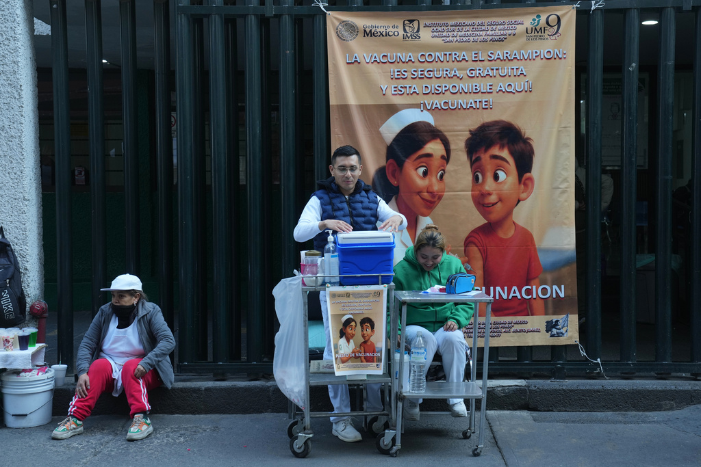 A health worker, center, prepares to administer a dose of the measles vaccine outside a public hospital in Mexico City, Wednesday, Feb. 4, 2026. (AP Photo/Marco Ugarte)