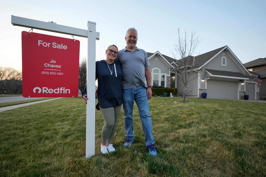 Gail and David Sanders stand in front of their home which they have been trying to sell Wednesday, March 25, 2026, in Olathe, Kan. (AP Photo/Charlie Riedel)