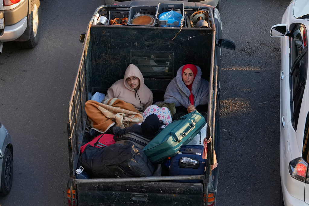 Displaced people fleeing Israeli strikes in southern Lebanon sit on a pickup at a highway that links to Beirut, in the southern port city of Sidon, Monday, March 2, 2026. (AP Photo/Mohammed Zaatari)