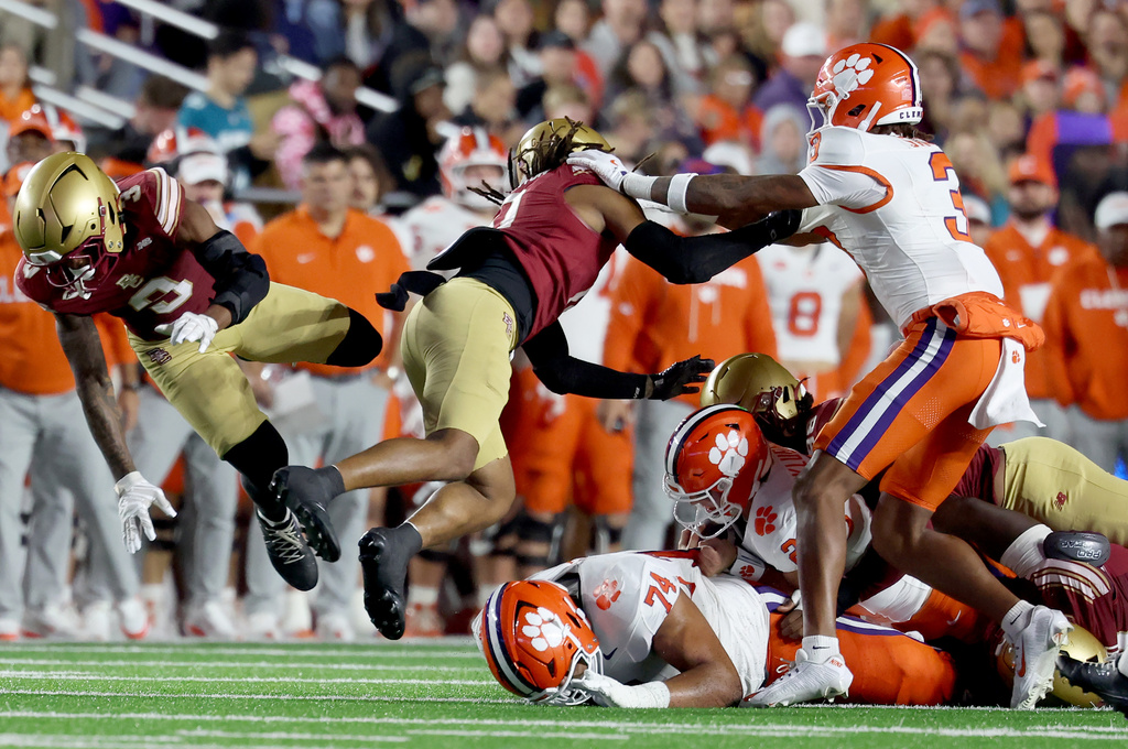 Boston College defensive backs Max Tucker, left, and Omar Thornton, center, fall to the turf after a tackle on Clemson quarterback Cade Klubnik (2) during the second half of an NCAA college football game Saturday, Oct. 11, 2025 in Boston. (AP Photo/Mark Stockwell)