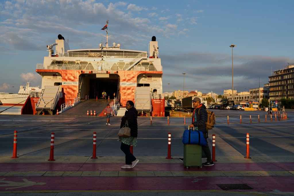 Passengers walk past a docked ferry in Piraeus port near Athens during a nationwide 24-hour strike, as labor unions demand higher wages and the withdrawal of a bill that changes work hours Wednesday, Oct. 1, 2025.(AP Photo/Petros Giannakouris)