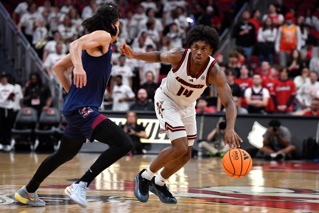 Louisville guard Adrian Wooley (14) drives past South Carolina State guard Florian Tenebay during the second half of an NCAA college basketball game in Louisville, Ky., Monday, Nov. 3, 2025. Louisville won 104-45. (AP Photo/Timothy D. Easley)