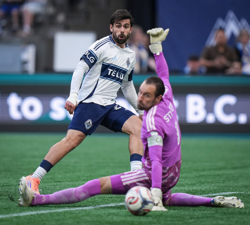 Vancouver Whitecaps' Brian White, left, scores against Austin FC goalkeeper Brad Stuver, right, during the second half of an MLS soccer match in Vancouver, British Columbia, Sunday, Sept. 13, 2026. (Darryl Dyck/The Canadian Press via AP)