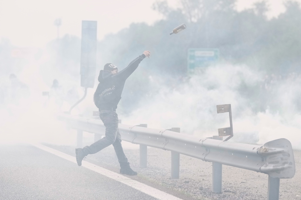 A pro-Palestinian demonstrator throws bottles during a demonstration part of a national general strike called by different unions to protest against the situation in Gaza two days after Israeli forces intercepted a Gaza-bound aid flotilla in the Mediterranean Sea, in Milan, Italy, Friday, Oct. 3, 2025. (AP Photo/Luca Bruno)
