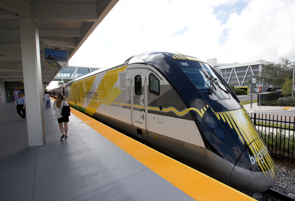 FILE -People walk near a Brightline train at a station, Jan. 11, 2018, in Fort Lauderdale, Fla. t. (AP Photo/Wilfredo Lee, File)