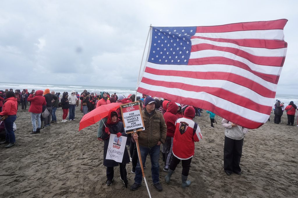 Cynthia Harb, foreground left, a physical education teacher at Marina Middle School, and her husband, Gus, middle, rally in support of the ongoing teachers strike at the San Francisco Unified School District with other teachers, students and supporters at Ocean Beach in San Francisco, Wednesday, Feb. 11, 2026. (AP Photo/Jeff Chiu)