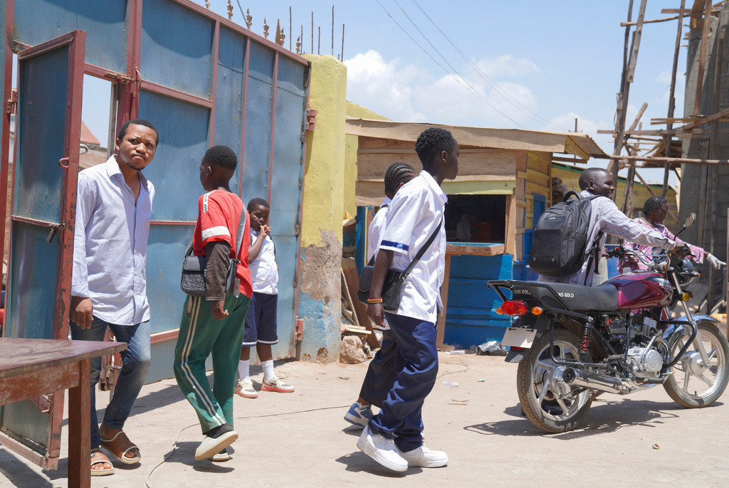People walk in front of a school on the first day of the new school year amid the Ebola virus outbreak, in Ituri, Congo, Tuesday, Sept. 1, 2026. (AP Photo/Dieudonne Dirole)