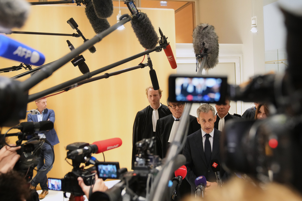 Former French President Nicolas Sarkozy speaks with the media after a Paris court sentenced him to 5 years after finding him guilty of criminal conspiracy in an alleged scheme to finance his 2007 campaign with funds from Libya, Thursday, Sept. 25, 2025 in Paris. (AP Photo/Christophe Ena)