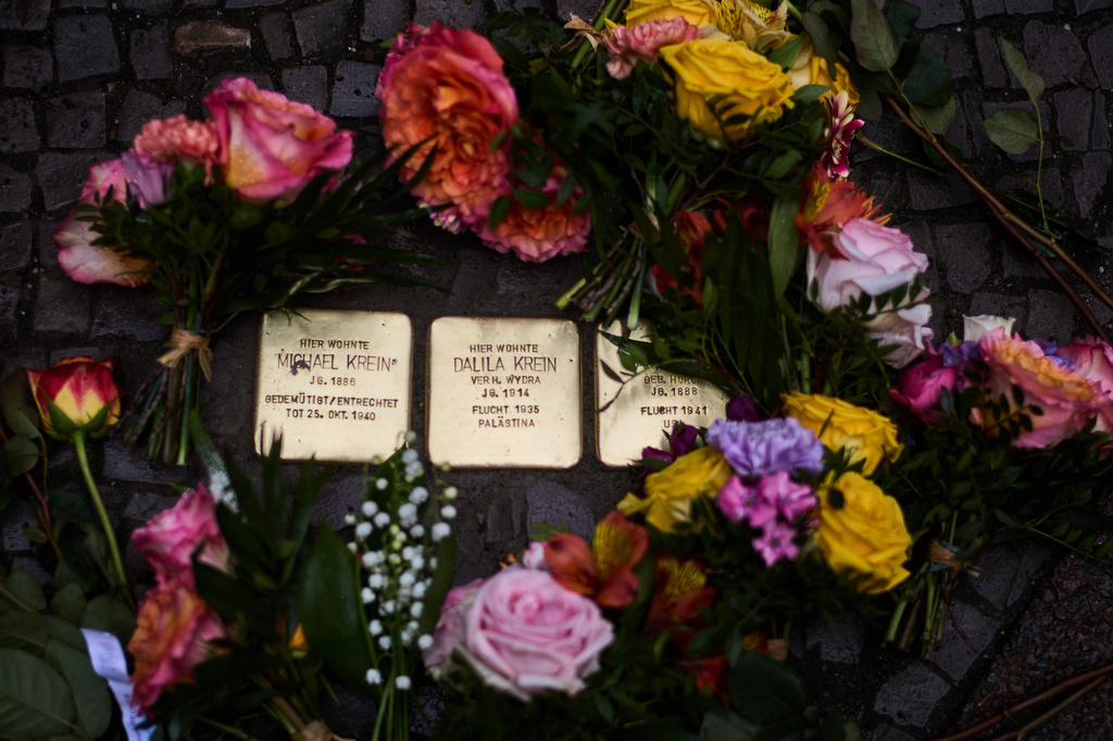 Flowers lay near palm-sized brass Holocaust plaques of the Krein family, after the so called "Stolpersteine", or "Stumbling Blocks" by artist Gunter Demnig, in Berlin, Germany, Wednesday, May 6, 2026. (AP Photo/Markus Schreiber)