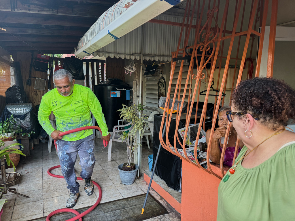 Municipal worker José Luiz López Obrero walks back to a water truck after he finishes up filling a cistern at the Villa Kennedy public housing complex in San Juan, Puerto Rico, Wednesday, June 10, 2026. (AP Photo/Danica Coto)