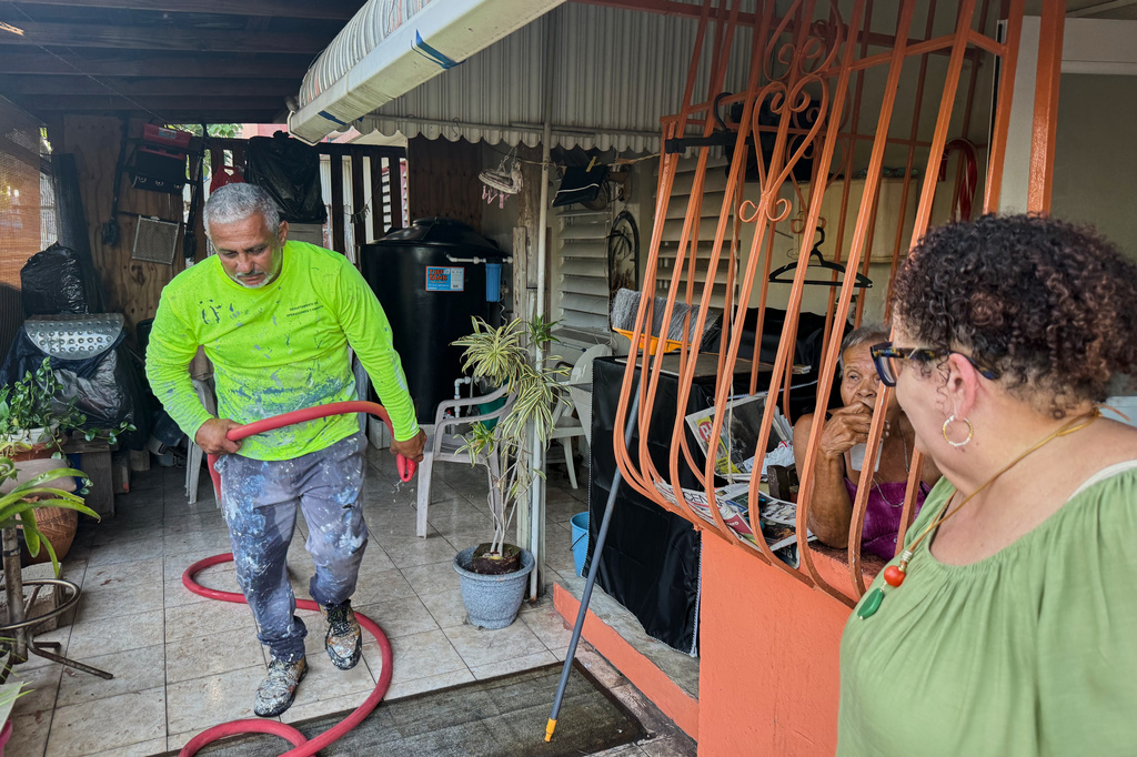 Municipal worker José Luiz López Obrero walks back to a water truck after he finishes up filling a cistern at the Villa Kennedy public housing complex in San Juan, Puerto Rico, Wednesday, June 10, 2026. (AP Photo/Danica Coto)