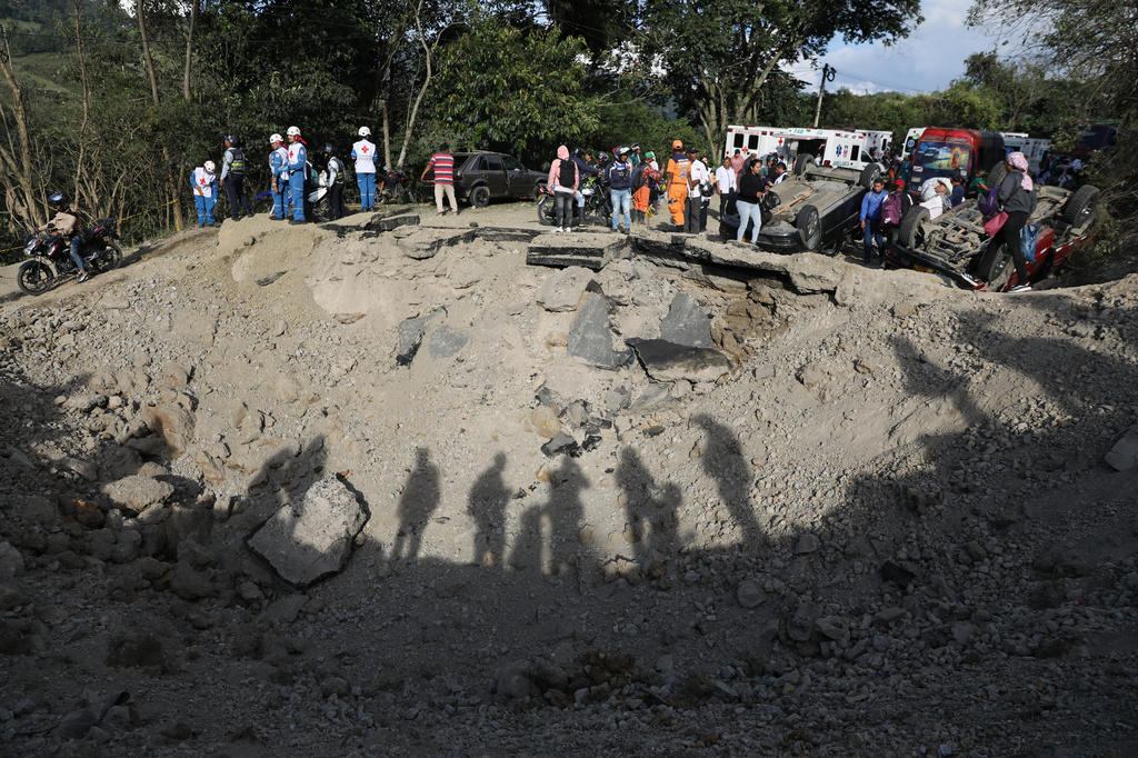 People look at vehicles damaged in an attack on the Pan-American Highway in Cajibio, Colombia, Saturday, April 25, 2026, that authorities said killed at least a dozen people and blamed on dissident groups of the former FARC rebels. (AP Photo/Santiago Saldarriaga)