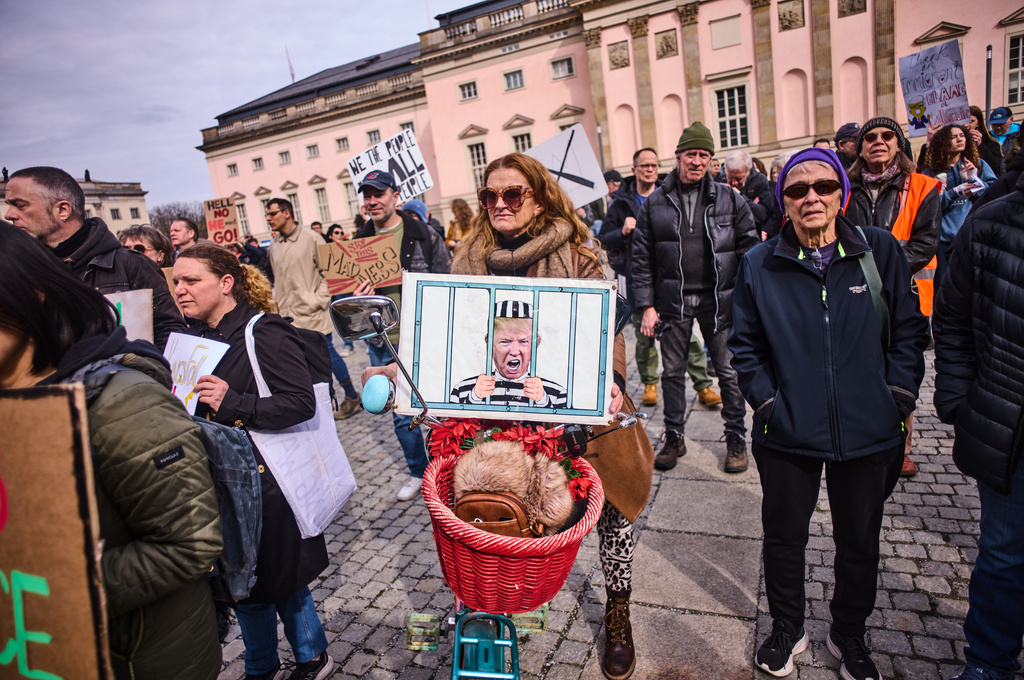 A woman holds a poster showing President Donald Trump behind bars as she attends a No Kings Protest against the US government in Berlin, Germany, Saturday, March 28, 2026. (AP Photo/Markus Schreiber)