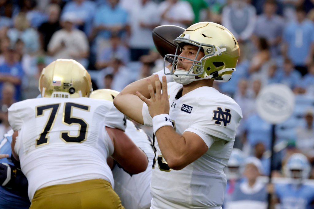 Notre Dame quarterback CJ Carr, right, looks to pass against North Carolina behind the block of offensive lineman Sullivan Absher (75) during the first half of an NCAA college football game Saturday, Oct. 3, 2026, in Chapel Hill, N.C. (AP Photo/Chris Seward)