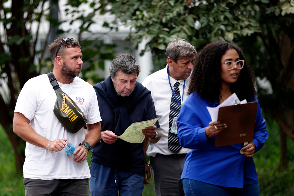 Oscar Vignale, second from left, the father of Argentine filmmaker Lucas Vignale, arrives at the Medical Examiner's Office to identify and claim the body of his son who died alongside others when two helicopters collided in midair and crashed in Rio de Janeiro, Brazil, Monday, June 15, 2026. (AP Photo/Bruna Prado)