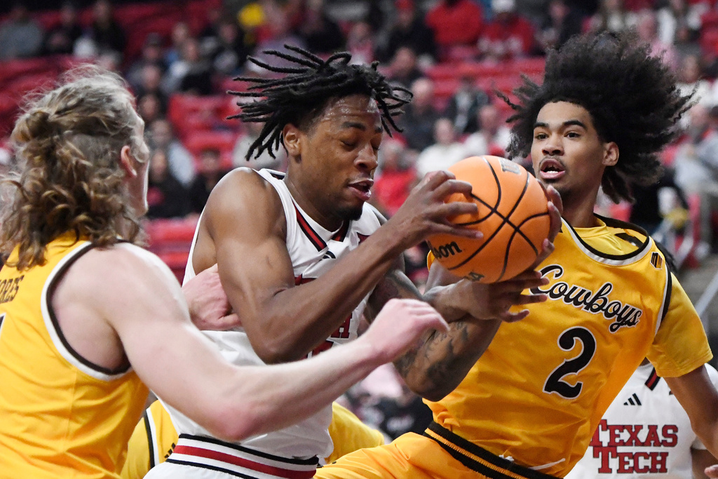 Texas Tech forward JT Toppin (15) and Wyoming guard Nasir Meyer (2) attempt to rebound the ball during the first half of an NCAA college basketball game Sunday, Nov. 30, 2025, in Lubbock, Texas. (AP Photo/Annie Rice)