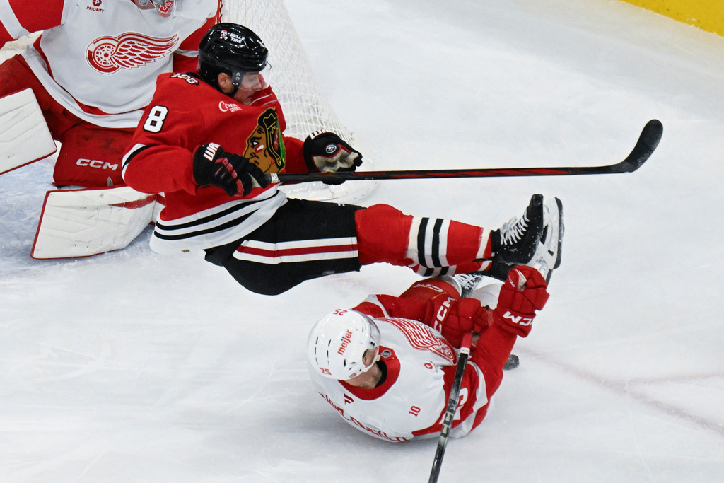 Chicago Blackhawks center Ryan Donato (8) is tripped by Detroit Red Wings defenseman Jacob Bernard-Docker (25) during the second period of an NHL hockey game, Saturday, Dec. 13, 2025, in Chicago. (AP Photo/Matt Marton)