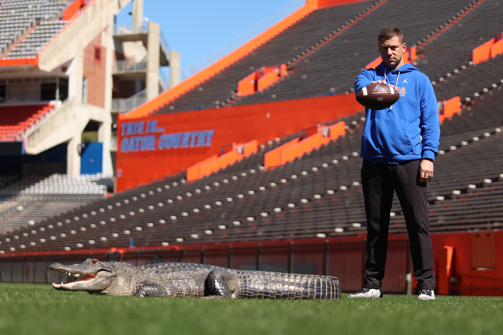 This photo provided by the University of Florida shows Florida football head coach Jon Sumrall posing with an alligator named Helene inside Ben Hill Griffin Stadium, Tuesday, Feb. 24, 2026, in Gainesville, Fla. (Jordan Perez/University of Florida via AP)