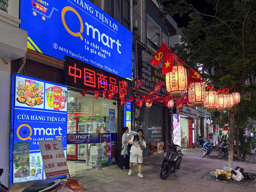 Two Vietnamese girls come out of a Vietnamese convenience store with signboard including Chinese characters in downtown Bac Ninh, Vietnam, Nov. 3, 2025. (AP Photo/Vincent Thian)