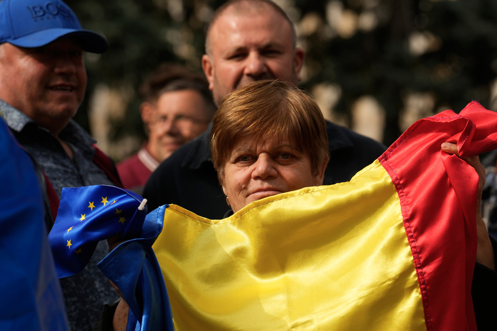 A woman holds Moldovan and EU flags during a pro-EU rally in Chisinau, Moldova, Monday, Sept. 29, 2025, after the parliamentary election. (AP Photo/Vadim Ghirda)