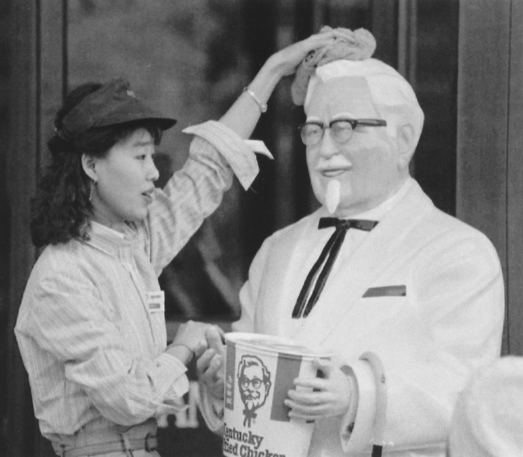 FILE - A young Chinese woman wipes a statue of Colonel Sanders, founder of Kentucky Fried Chicken, in front of the Beijing restaurant on May 11, 1991. (AP Photo/Mark Avery, File)