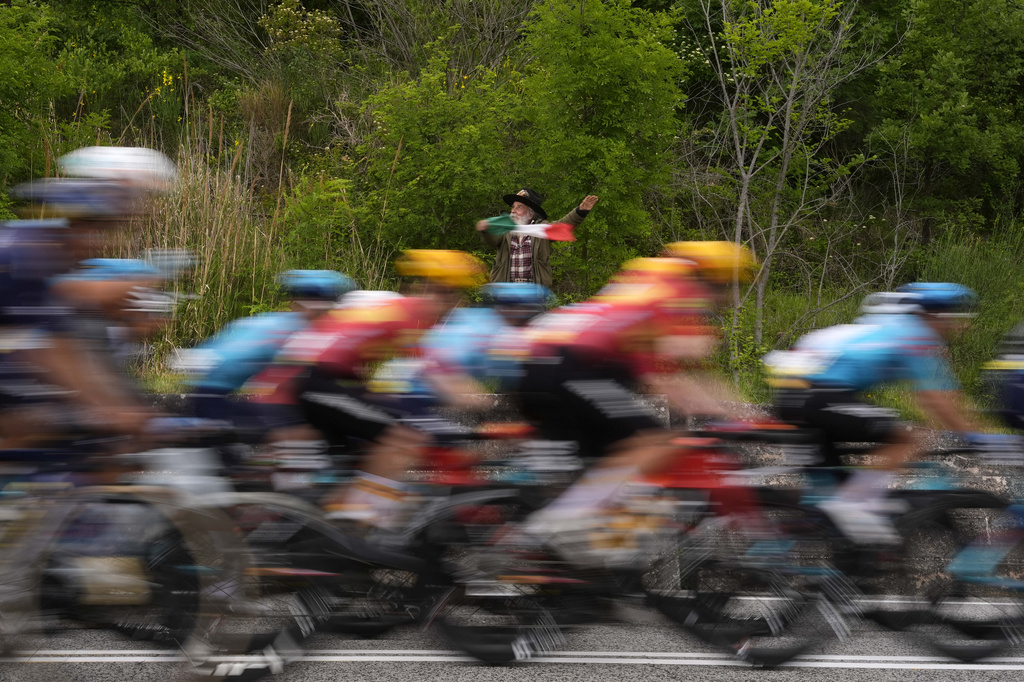 The pack rides past a fan waving an Italian flag, during the 7th stage of the Giro d'Italia cycling race, from Formia to Blockhaus, Italy, Friday May 15, 2026. (Fabio Ferrari/LaPresse via AP)