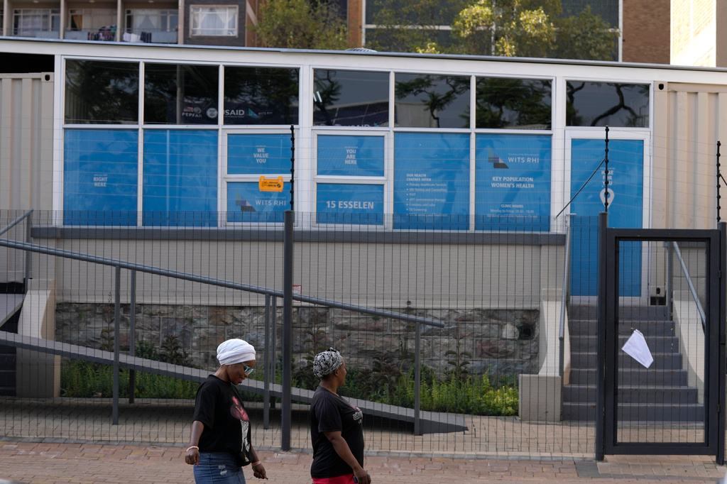 FILE - Women walk past a closed clinic run by WITS Reproductive Health Institute (RHI) as a sign on the gate reads "USAID has served the WITS RHI Key Populations Programme a notice to pause programme implementation. As of Tuesday, 28 January, we are unable to provide services until further notice." in Hillbrow, Johannesburg, South Africa, Feb. 27, 2025. (AP Photo/Themba Hadebe, File)
