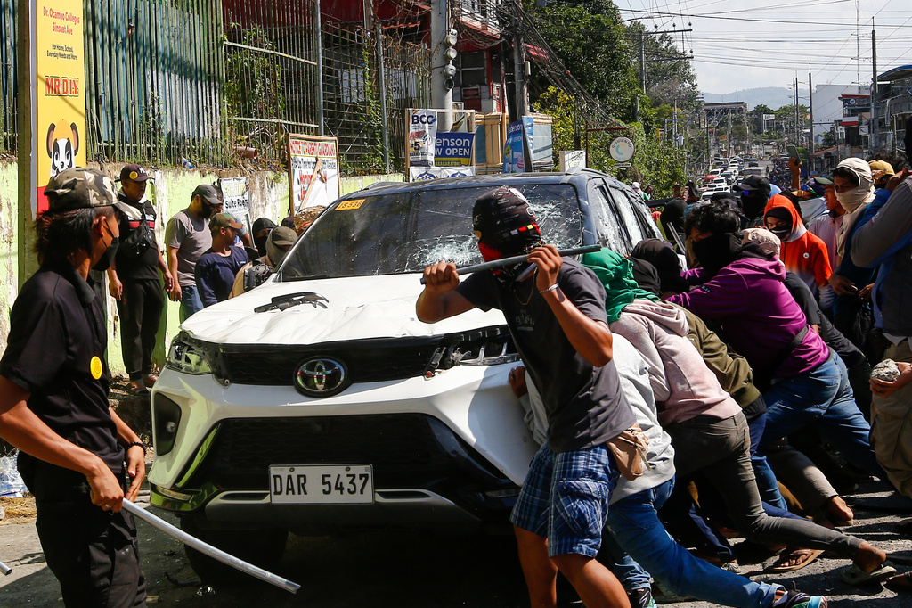 A group attacks a vehicle from an opposing group outside a school used as a polling center during the Bangsamoro Autonomous Region in Muslim Mindanao parliamentary elections in Cotabato city, southern Philippines, Monday, Sept. 14, 2026. (AP Photo)