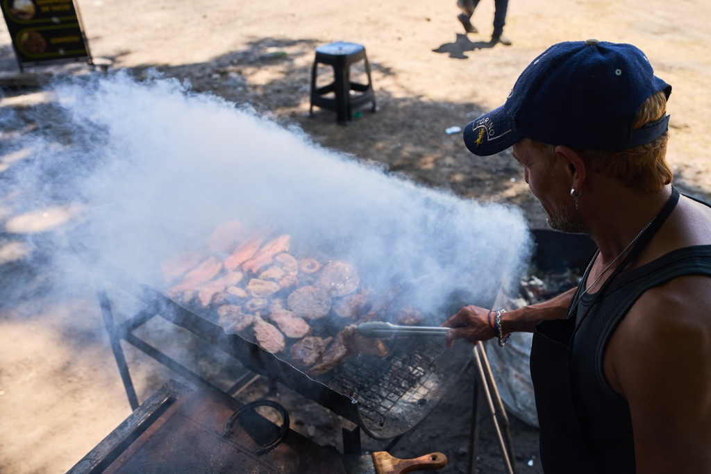 Cesar Tousedo grills meat to sell at a street stall in Buenos Aires, Argentina, Tuesday, Feb. 10, 2026. (AP Photo/Rodrigo Abd)