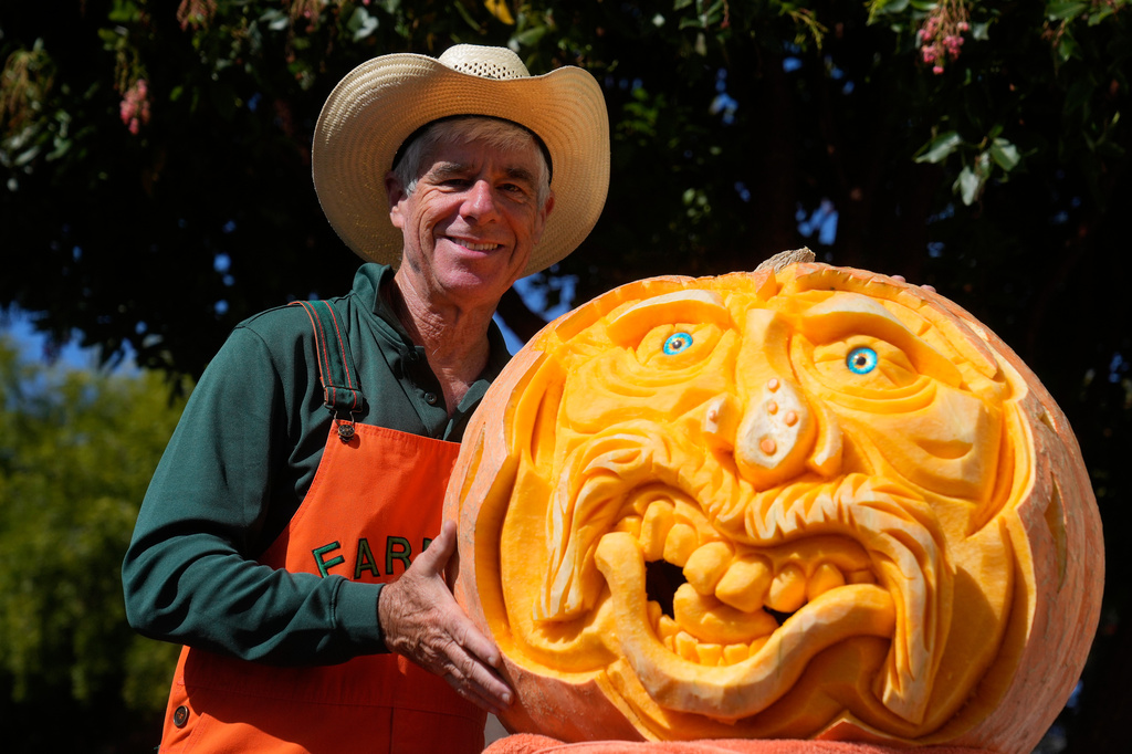 Farmer Mike Valladao poses next to a pumpkin he carved at the Safeway World Championship Pumpkin Weigh-Off, Monday, Oct. 12, 2026, in Half Moon Bay, Calif. (AP Photo/Jeff Chiu)