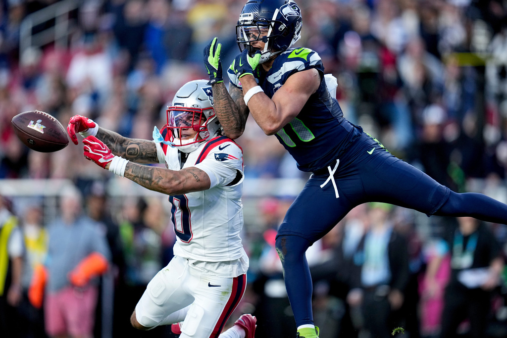 New England Patriots cornerback Christian Gonzalez (0) breaks up a pass intended for Seattle Seahawks wide receiver Jaxon Smith-Njigba, right, during the first half of the NFL Super Bowl 60 football game, Sunday, Feb. 8, 2026, in Santa Clara, Calif. (AP Photo/Sue Ogrocki)