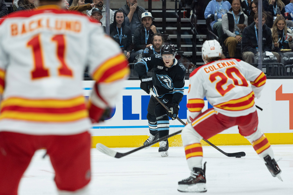 Utah Mammoth defenseman Olli Maatta (2) shot the puck against Calgary Flames left wing Blake Coleman (20) and center Mikael Backlund (11) during the second half of an NHL hockey game Wednesday, Oct. 15, 2025, in Salt Lake City. (AP Photo/Melissa Majchrzak)