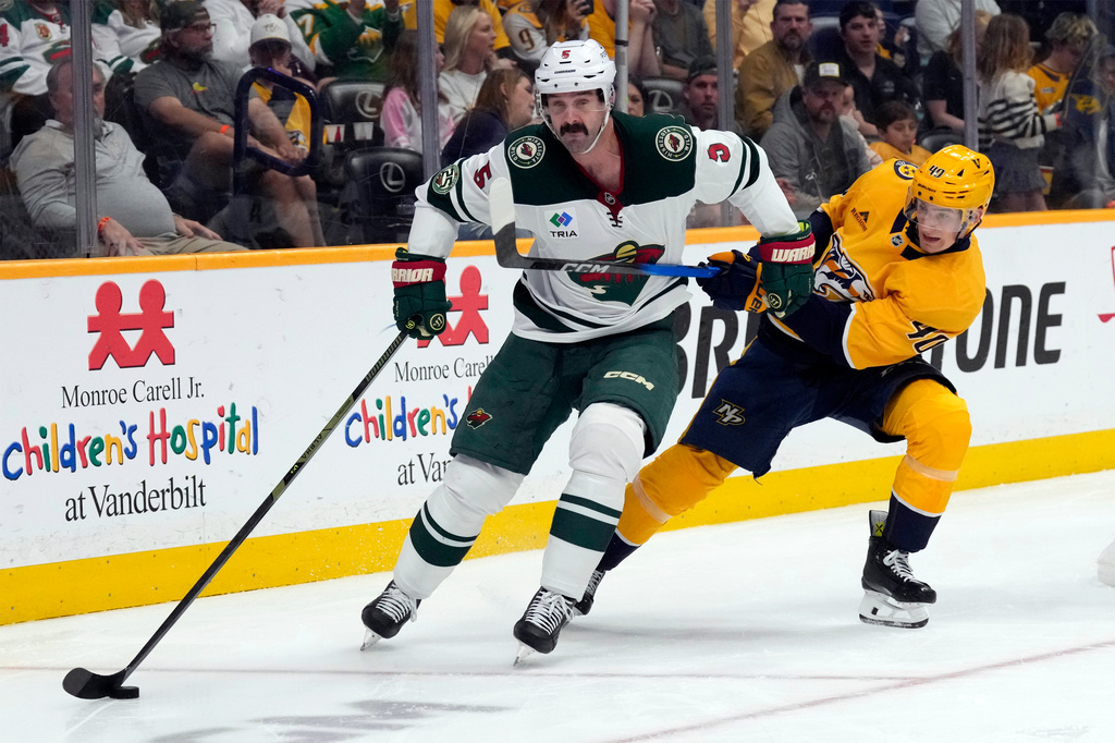 Minnesota Wild defenseman Jake Middleton (5) moves the puck away from Nashville Predators center Fedor Svechkov (40) during the second period of an NHL hockey game Saturday, April 11, 2026, in Nashville, Tenn. (AP Photo/Mark Humphrey)