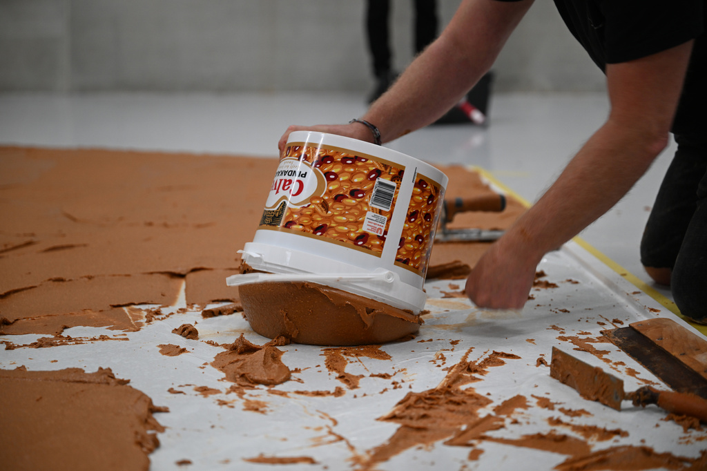 Workers spread peanut butter on a floor to recreate the "Peanut Butter Floor" artwork in tribute to Dutch artist Wim T. Schippers at the Museum Boijmans Van Beuningen in Rotterdam, Netherlands, Friday, July 3, 2026. (AP Photo/Mouneb Taim)