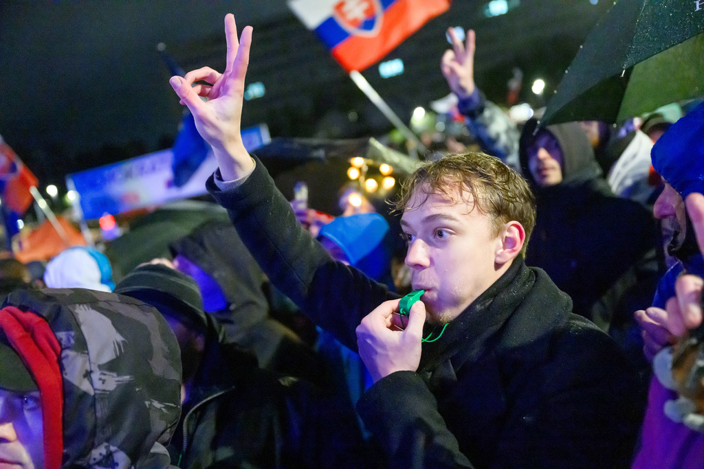 A demonstrant blows a whistle and shows the victory sign during a rally to celebrate the 36th anniversary of the pro-democratic Velvet Revolution, in Bratislava, Slovakia, Monday, Nov. 17, 2025. (Jaroslav Novak/TASR via AP)