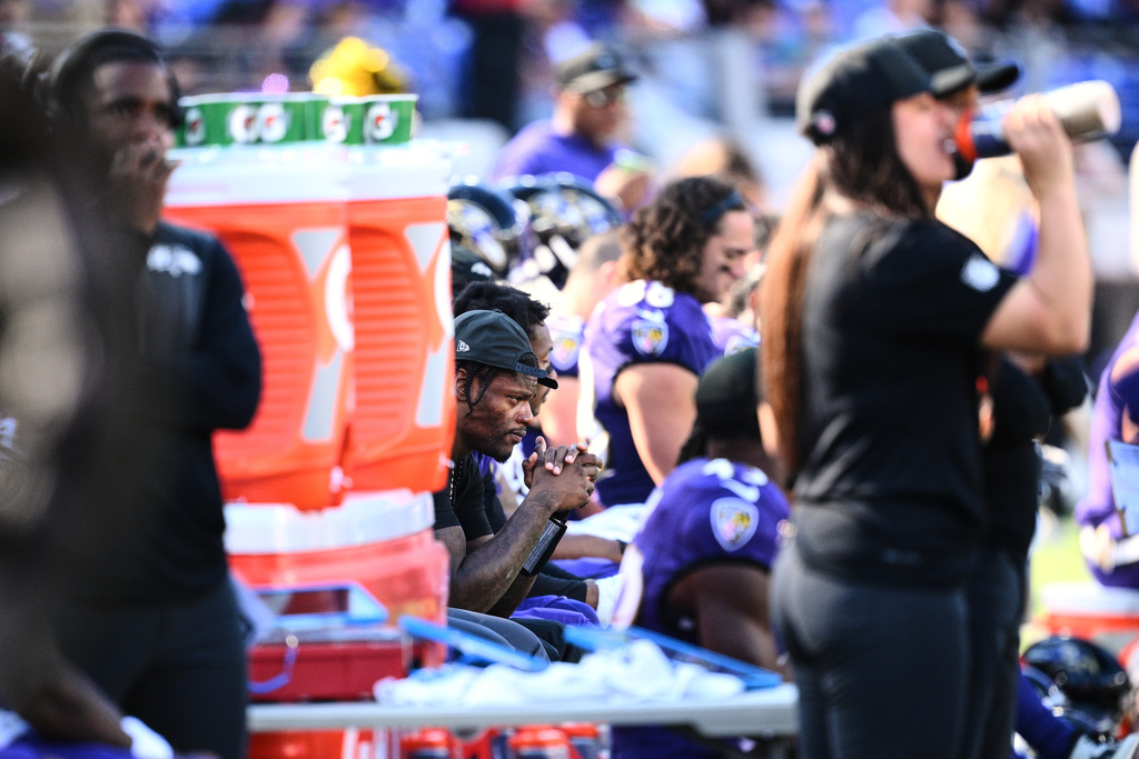 Baltimore Ravens quarterback Lamar Jackson, center, sits on the sideline during the second half of an NFL football game against the Houston Texans, Sunday, Oct. 5, 2025, in Baltimore. (AP Photo/Nick Wass)