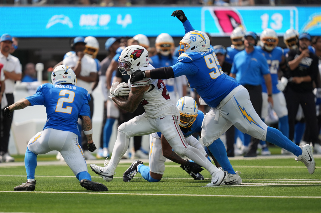 Arizona Cardinals running back Tyler Allgeier, middle, runs against Los Angeles Chargers cornerback Elijah Molden (2), defensive tackle Jamaree Caldwell (99) and linebacker Del'Shawn Phillips during the second half of an NFL football game, Sunday, Sept. 13, 2026, in Inglewood, Calif. (AP Photo/Gregory Bull)
