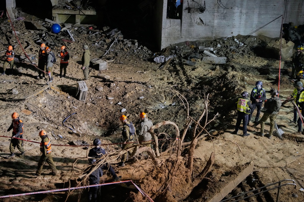 Israeli security forces and rescue teams inspect the crater left by an Iranian missile in Arad, southern Israel, Sunday, March 22, 2026. (AP Photo/Ohad Zwigenberg)