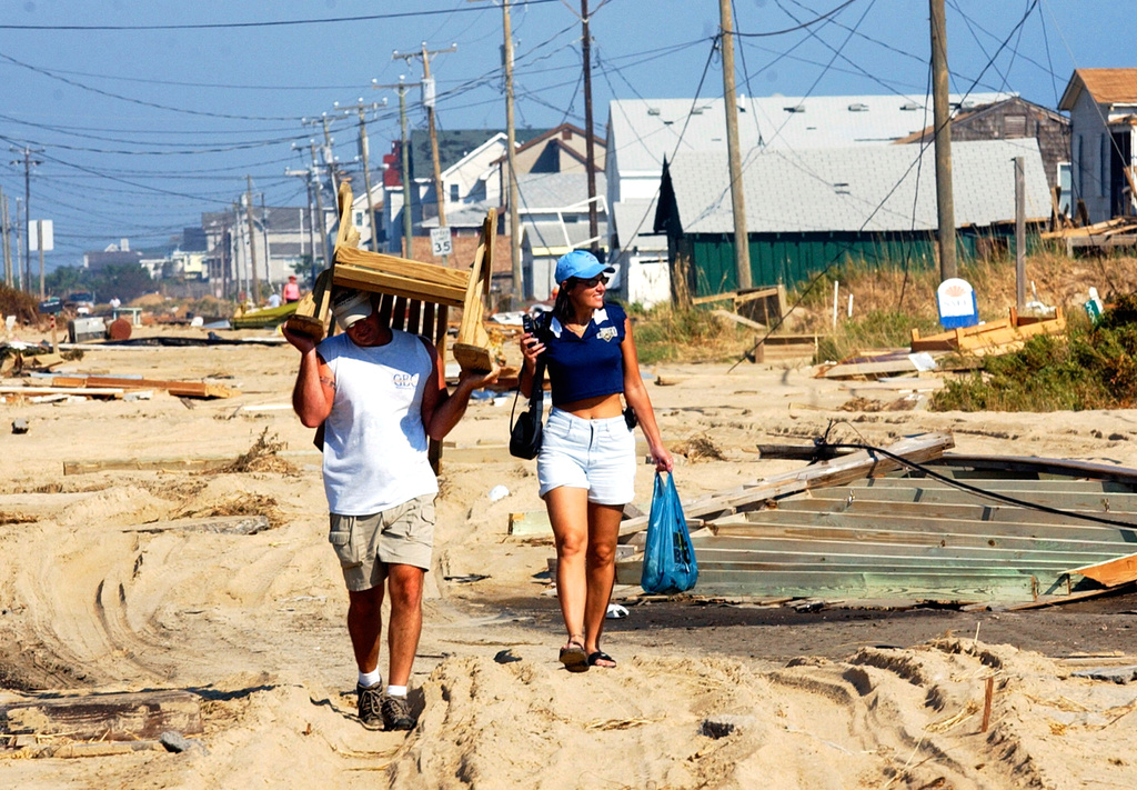 FILE - Ed Manzi of Dover, Del., carries a wooden rocking chair down the middle of Highway 12 in Kitty Hawk, N.C., on the Outer Banks, after returning to the area to check on his beach home with his wife Pam, Sept. 21, 2003. (AP Photo/Dave Martin, File)