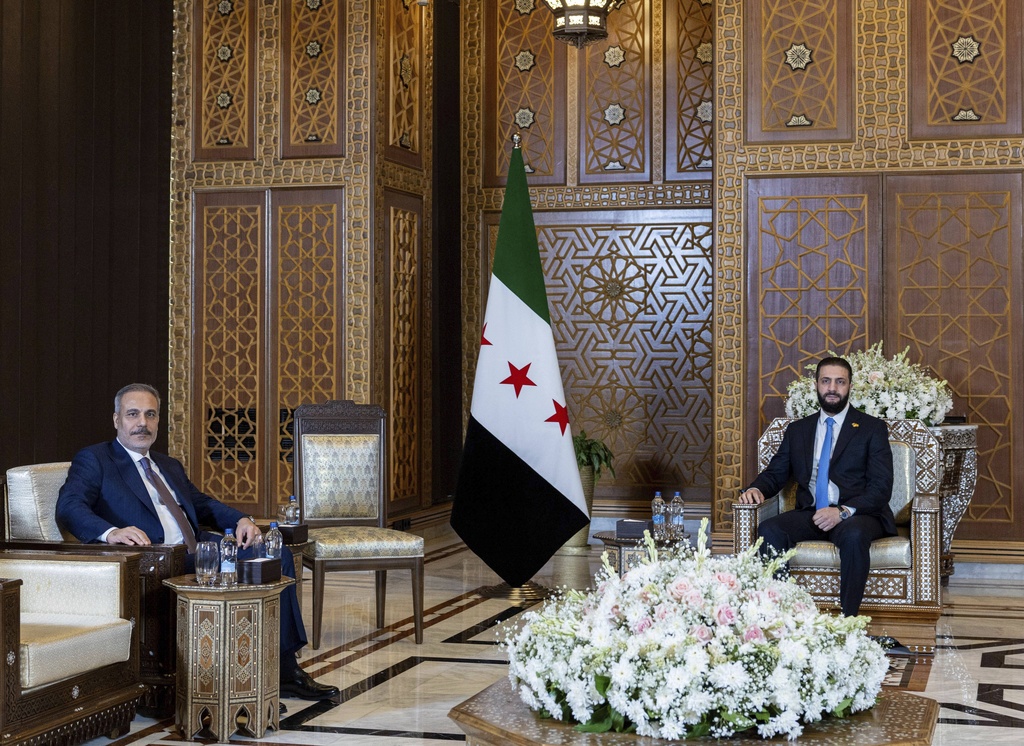 In this handout photo released by the Turkish Foreign Ministry press service, Turkish Foreign Minister Hakan Fidan, left, sits with Syria's interim President Ahmad Al-Sharaa, during their meeting in Damascus, Syria, Thursday, Aug. 7, 2025. (Turkish Foreign Ministry via AP)