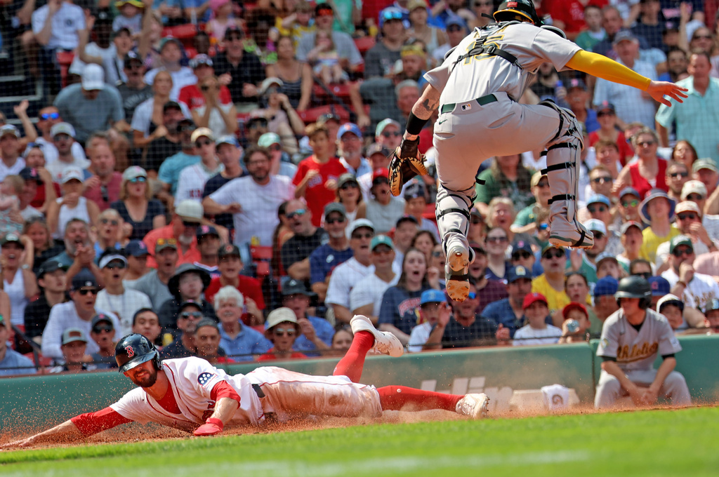 Boston Red Sox's Eli White, left, slides to home plate to score as Athletics catcher Jonah Heim, top right, leaps out of the way during the fifth inning of a baseball game, Sunday, Aug. 9, 2026, in Boston. (AP Photo/Mark Stockwell)