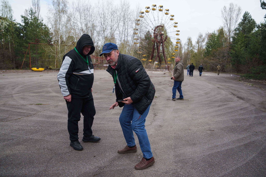 Workers sent to clean up contamination from the Chernobyl nuclear power plant accident walk in the nearby abandoned town of Prypiat, Ukraine, during a return visit to the region, Tuesday, April 21, 2026. (AP Photo/Evgeniy Maloletka)