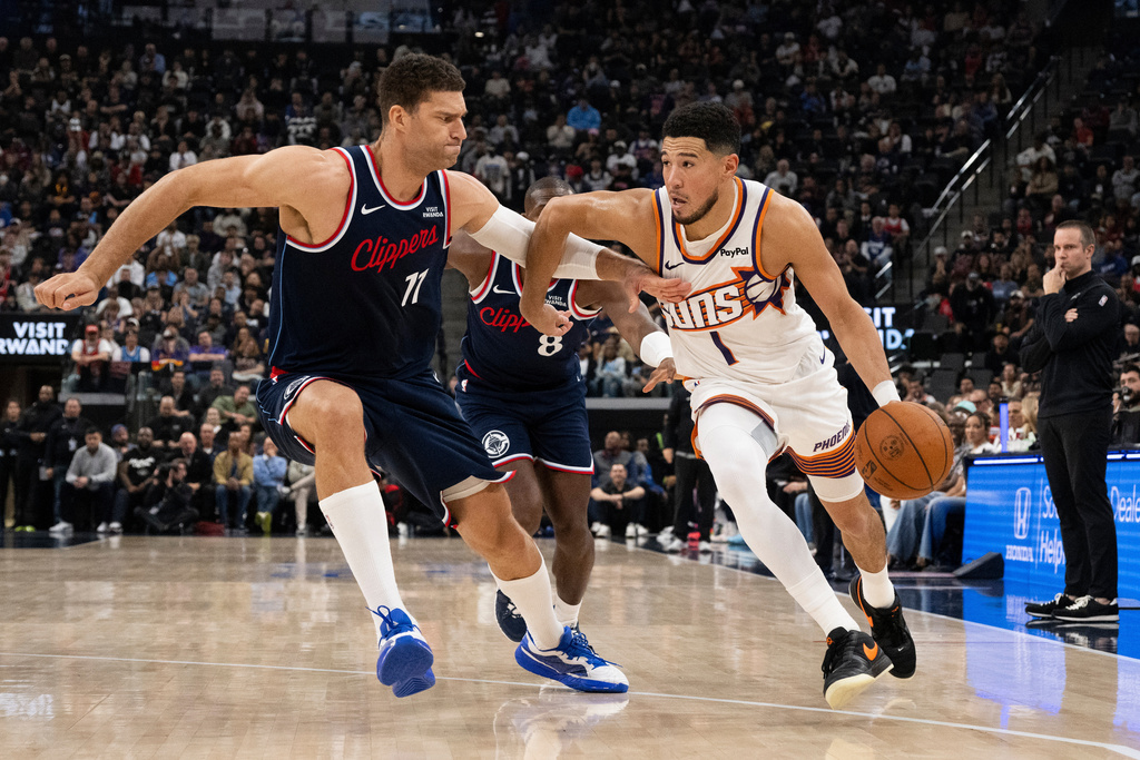 Phoenix Suns guard Devin Booker (1) drives to the basket as Los Angeles Clippers center Brook Lopez (11) defends during the first half of an NBA basketball game Friday, Oct. 24, 2025, in Inglewood, Calif. (AP Photo/Kyusung Gong)