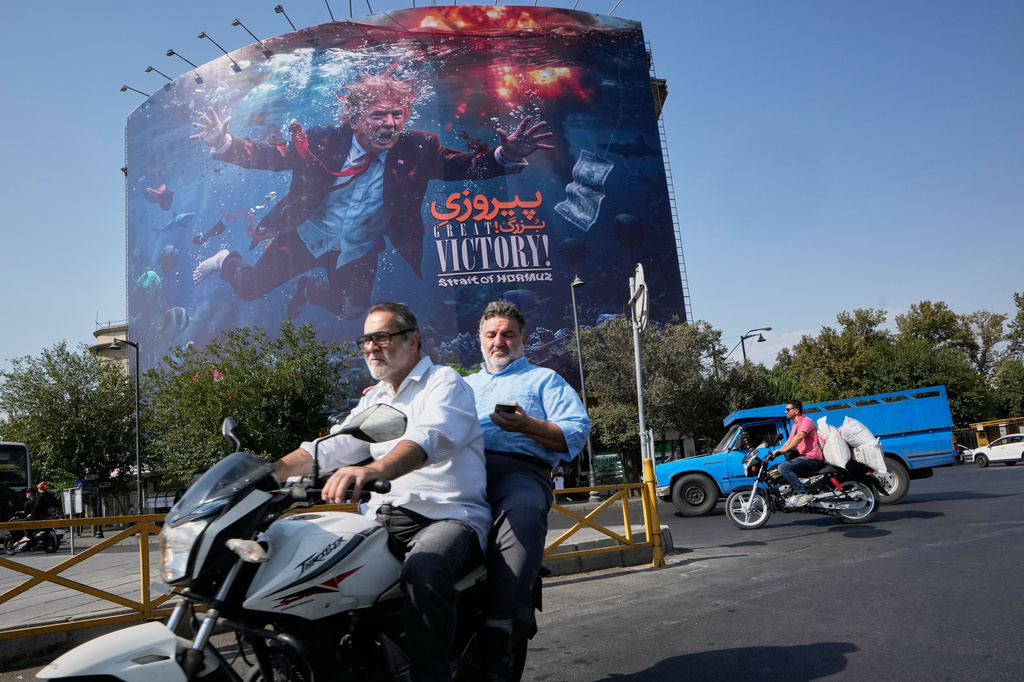 Motorcyclists pass a billboard depicting U.S. President Donald Trump underwater amid explosions, with the words "Great Victory! Strait of Hormuz," in Tehran, Iran, Monday, Aug. 24, 2026. (AP Photo/Vahid Salemi)