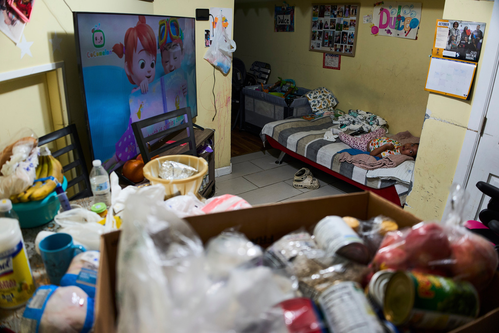 A disabled girl looks back at food donated by her Catholic Church, the Shrine of the Sacred Heart, as she watches cartoons at home in Washington, Oct. 11, 2025. (AP Photo/Luis Andres Henao)