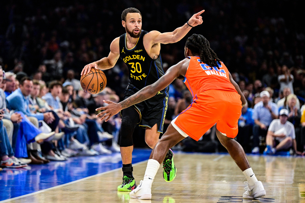Golden State Warriors guard Stephen Curry (30) gestures against Oklahoma City Thunder guard Cason Wallace (22) during the first half of an NBA basketball game, Tuesday, Nov. 11, 2025, in Oklahoma City. (AP Photo/Gerald Leong)