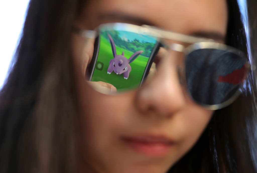 FILE - A mobile screen is reflected on a fan's sunglasses as she plays "Pokemon Go" in Hong Kong, on July 25, 2016. (AP Photo/Kin Cheung, File)