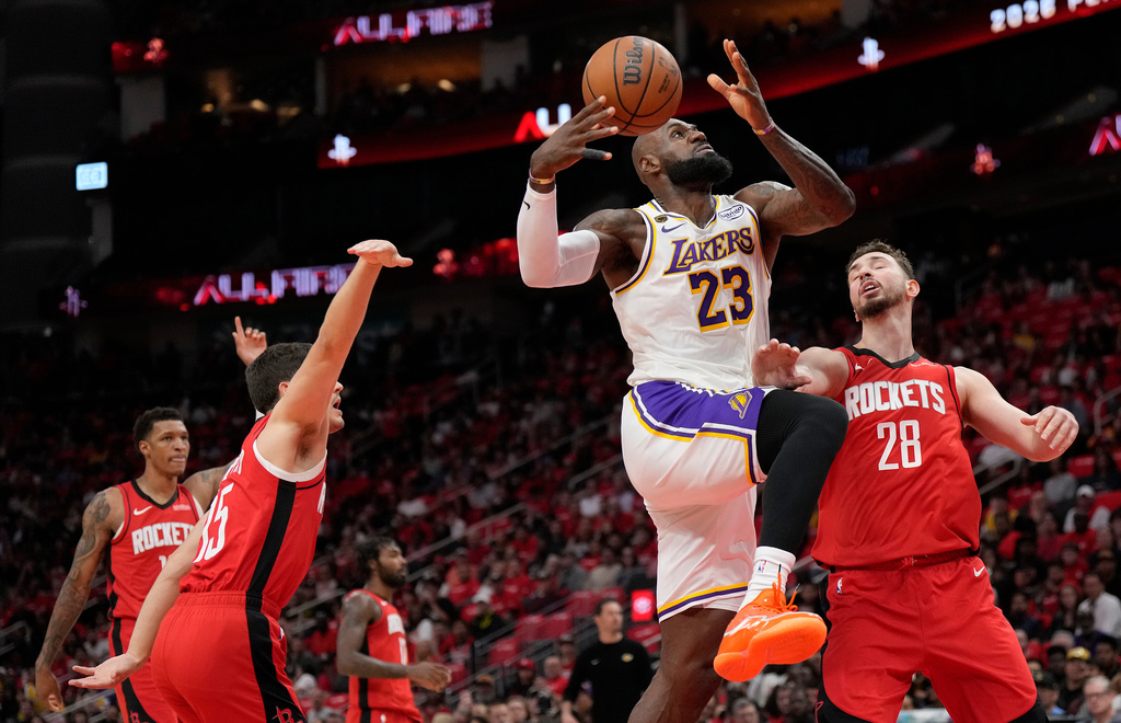 Los Angeles Lakers forward LeBron James (23) goes to the basket against Houston Rockets' Reed Sheppard, left, and Alperen Sengun (28) during the first half in Game 4 of a first-round NBA basketball playoffs series, Sunday, April 26, 2026, in Houston. (AP Photo/Karen Warren)