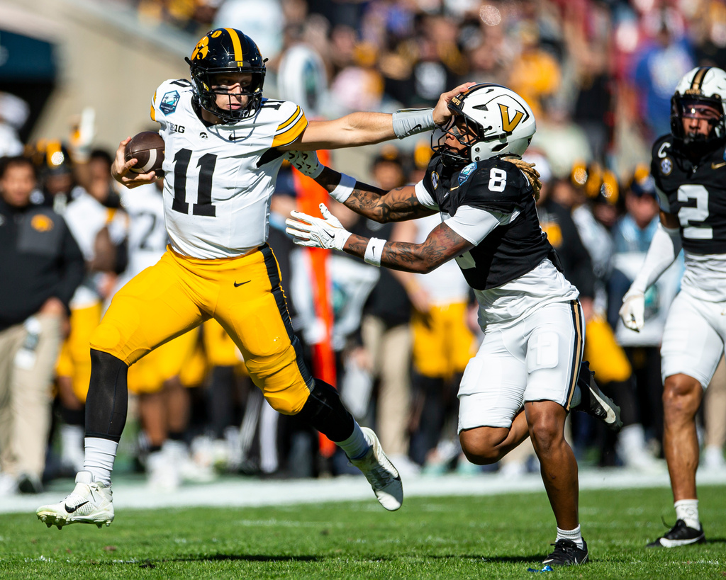 Iowa Hawkeyes quarterback Mark Gronowski (11) stiff arms Vanderbilt safety CJ Heard (8) during the 2025 ReliaQuest Bowl game between the Vanderbilt Commodores and the Iowa Hawkeyes at Raymond James Stadium in Tampa, Fla., on Wednesday, Dec. 31, 2025. (Nick Rohlman/The Gazette via AP)